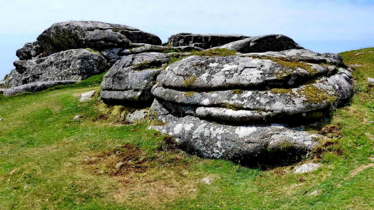 Before reaching the hilltop rocks, there are other rocks on the left that bear a small plaque that can be seen above