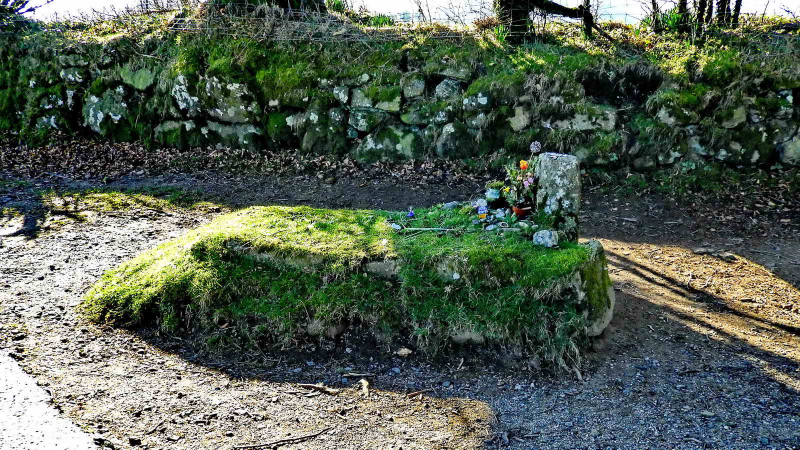 The grave is never left without flowers, yet nobody claims credit for the placing of them. More recently, small coins and other offerings have started to be left by visitors